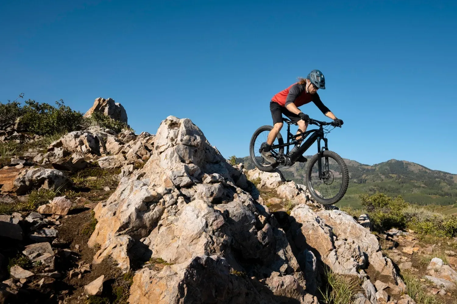 Ciclista NEXTA: Corporativa en descens rocós sota cel blau.