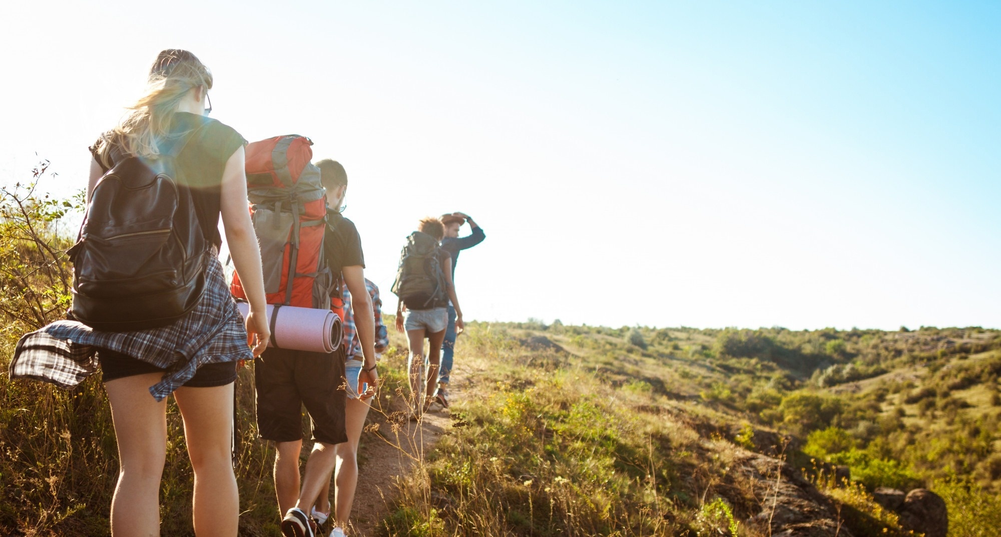 a group of people with backpacks are hiking up a hill