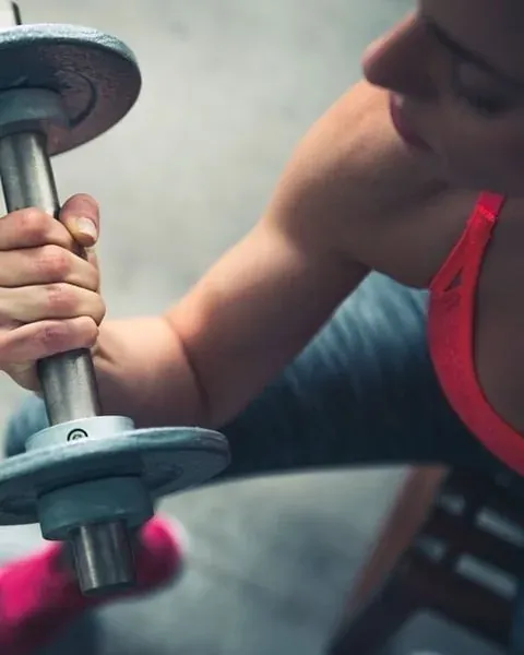 NEXTA: Corporativa - Mujer levantando pesa, entrenando en gimnasio.