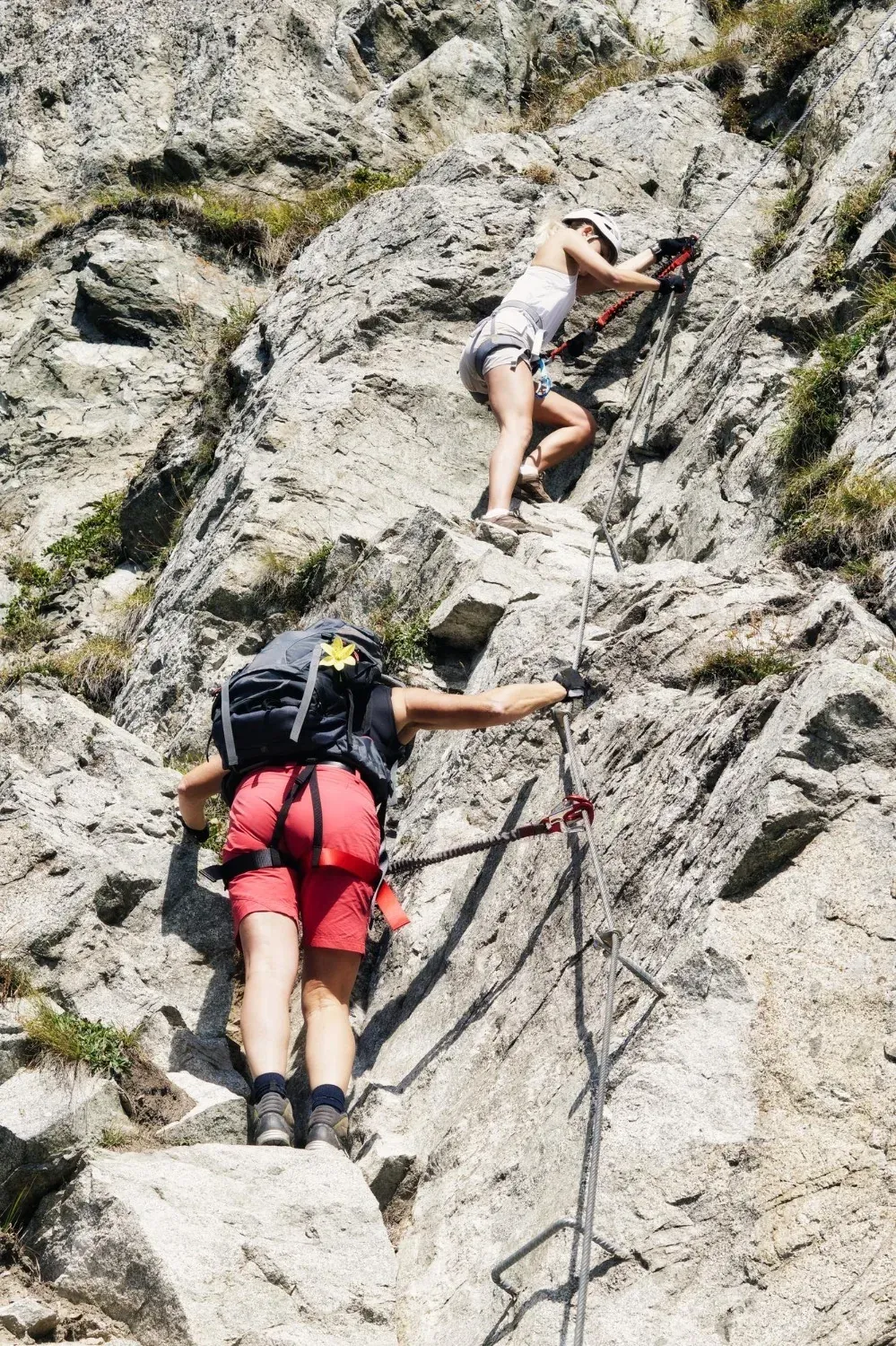 NEXTA: Corporativa - Two hikers climbing a via ferrata route on the mountain.