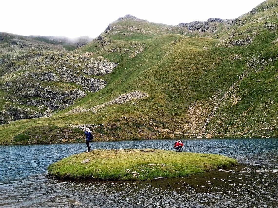 dos personas se paran en una pequeña isla en medio de un lago