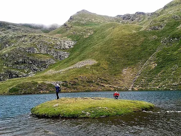 dos personas se paran en una pequeña isla en medio de un lago