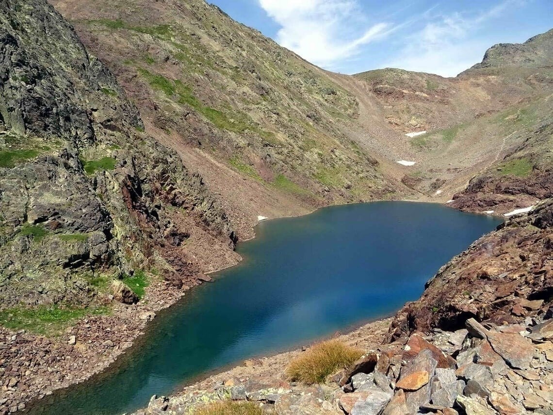 un pequeño lago rodeado de montañas y rocas
