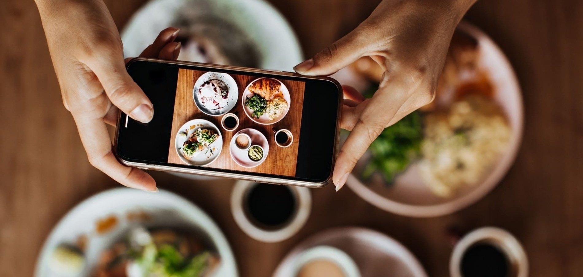 una persona toma una foto de platos de comida con un teléfono inteligente