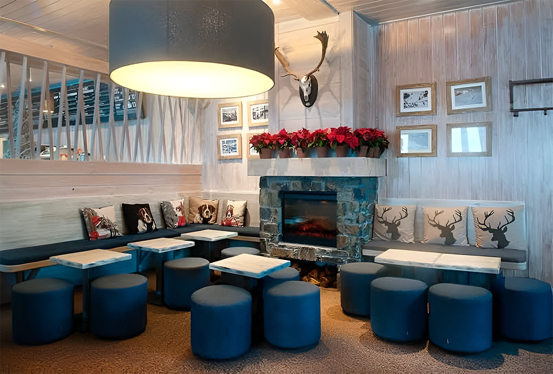 una sala de estar con mesas y taburetes azules y una chimenea