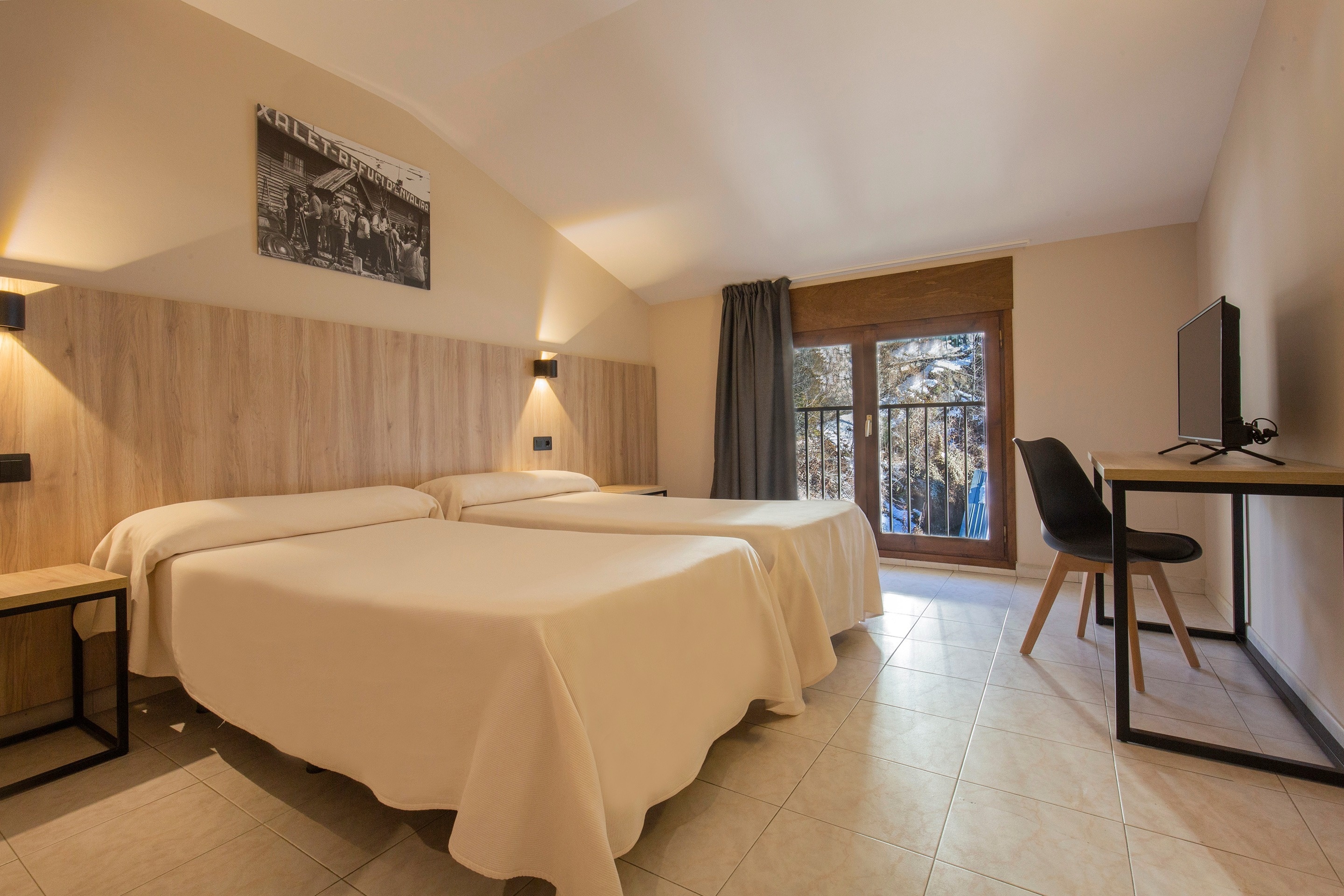 a hotel room with two beds a desk and a television