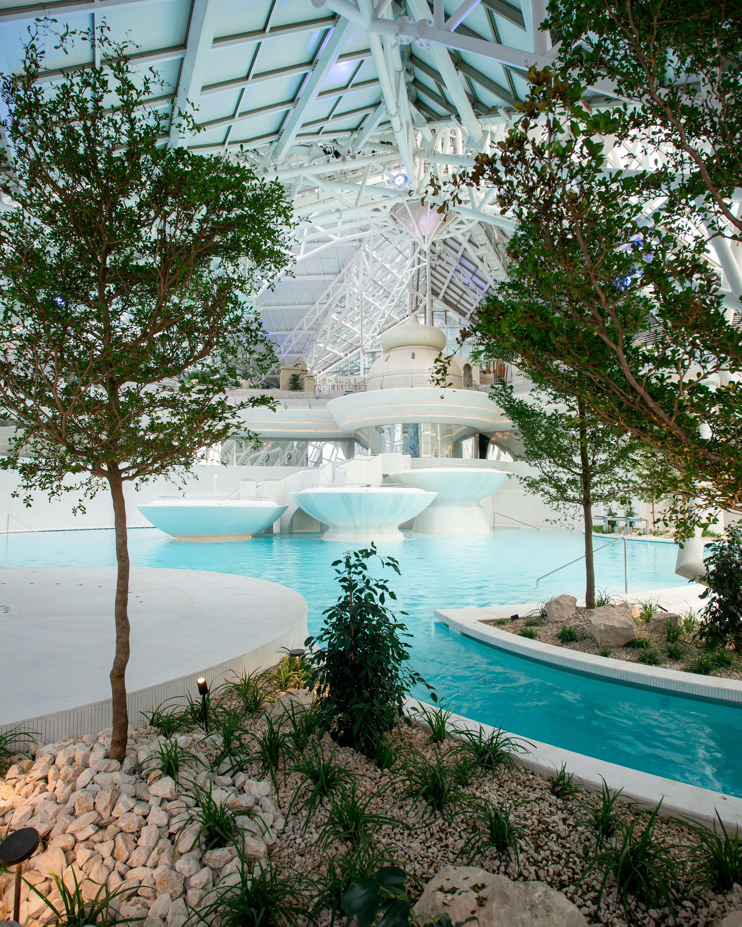 una piscina dentro de un edificio con árboles y rocas