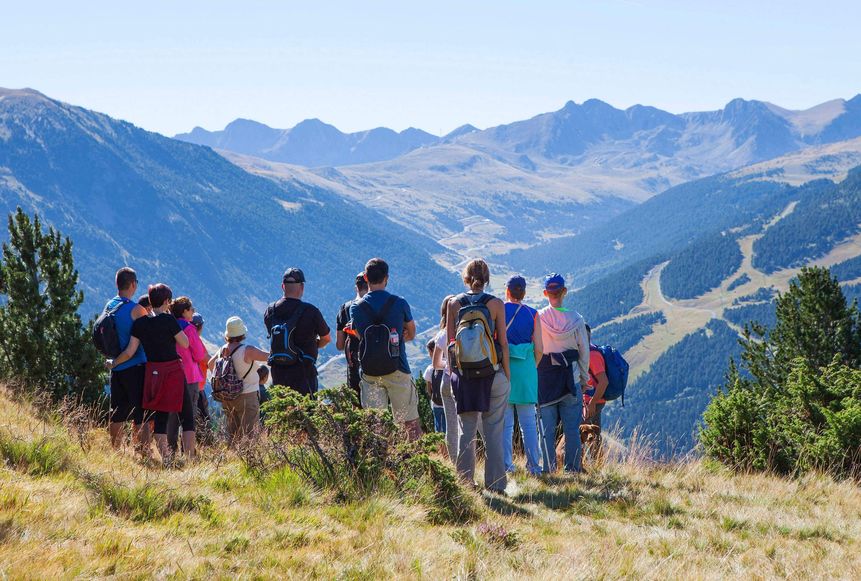 a group of people standing on top of a hill looking at the mountains