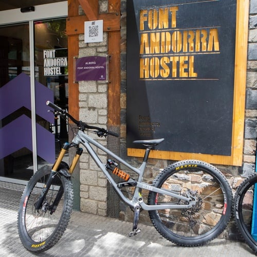 dos bicicletas están estacionadas frente a un cartel que dice hostal font andorra