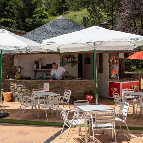 a man stands behind a counter under an umbrella that says heineken