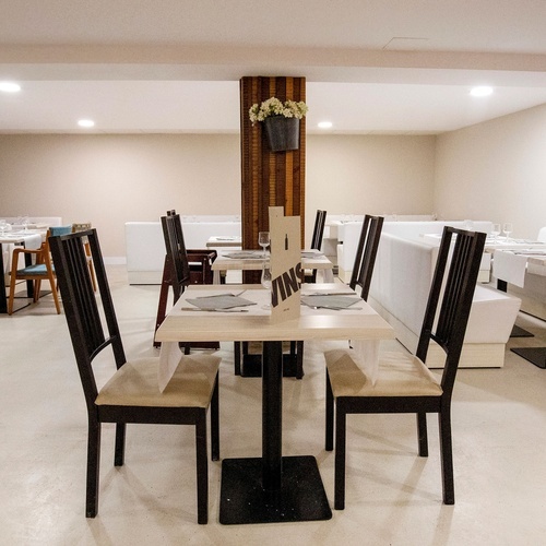 a dining room with tables and chairs and a vase of flowers on the wall