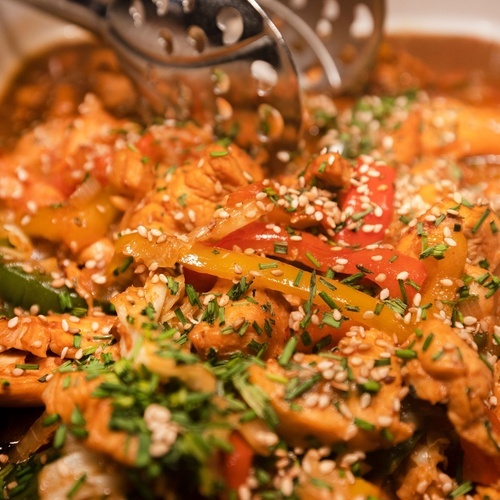 a casserole dish filled with chicken and vegetables with sesame seeds on top