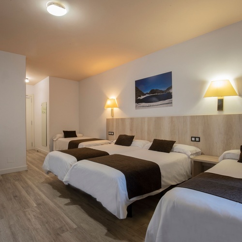 una habitación de hotel con tres camas y una televisión