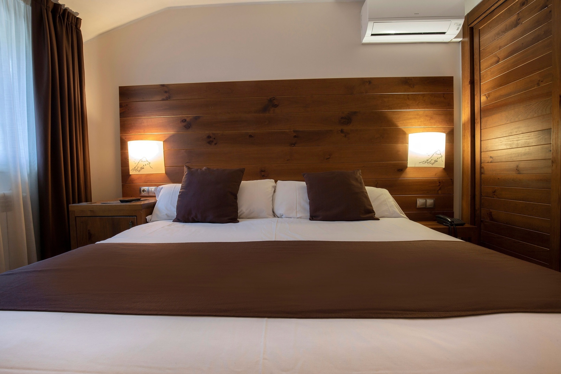 a hotel room with a bed and a wooden headboard