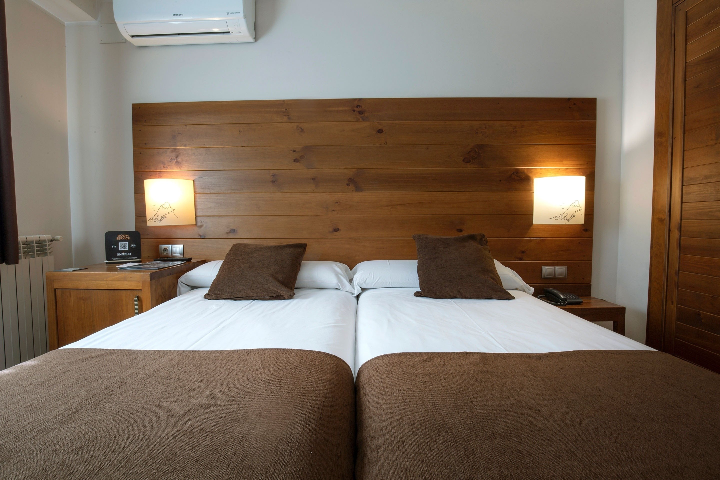 a hotel room with two beds and a wooden headboard