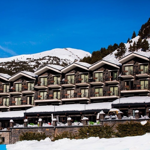 ein großes Gebäude mit vielen Balkonen und einem schneebedeckten Berg im Hintergrund