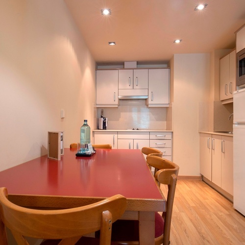 a small kitchen with a red table and chairs