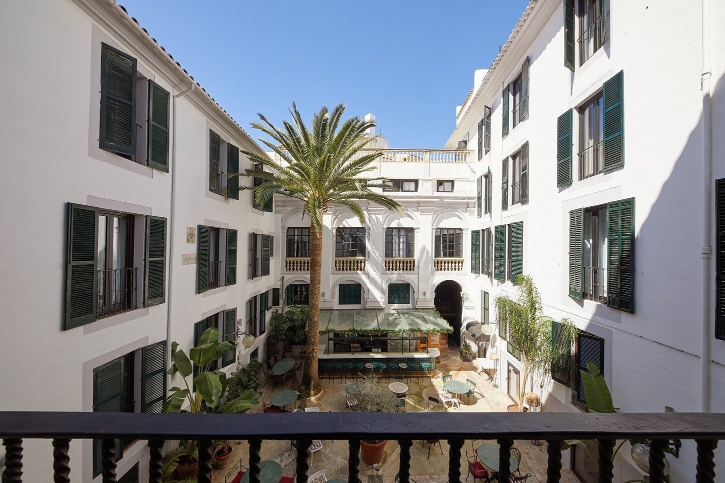 un edificio blanco con persianas verdes y una palmera