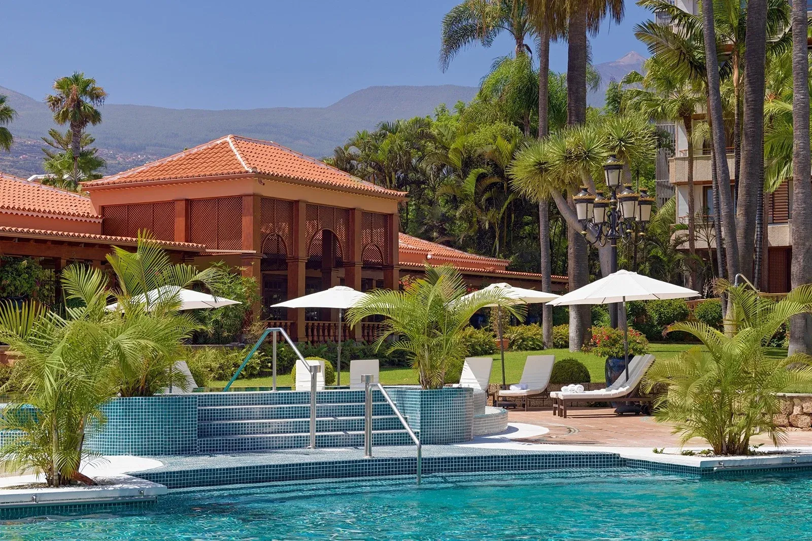 Hotel Botanico: campo da tennis blu vicino a piscine e palme.