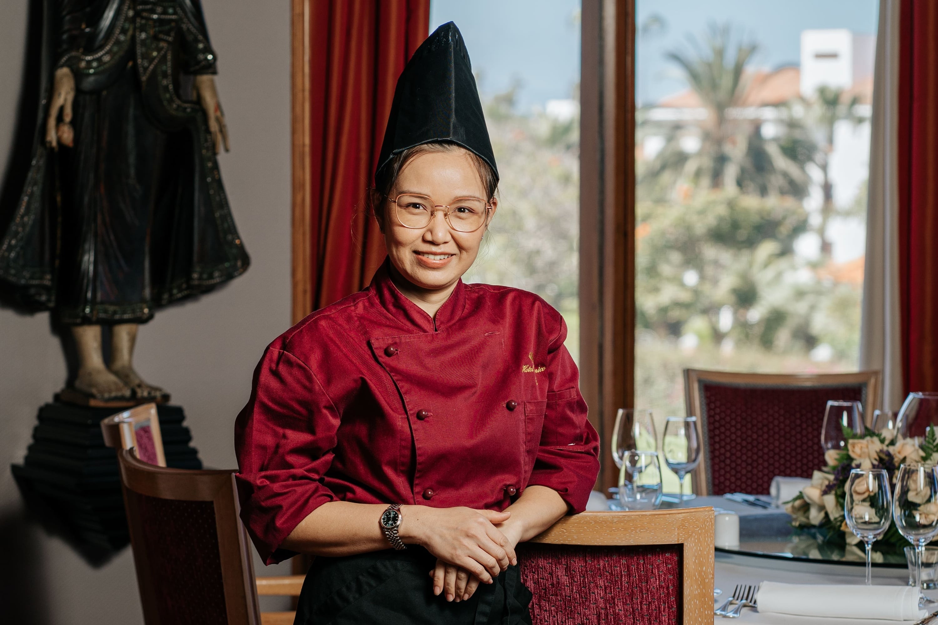 En un elegante restaurante de inspiración asiática, varias personas disfrutan de una comida servida por un camarero.