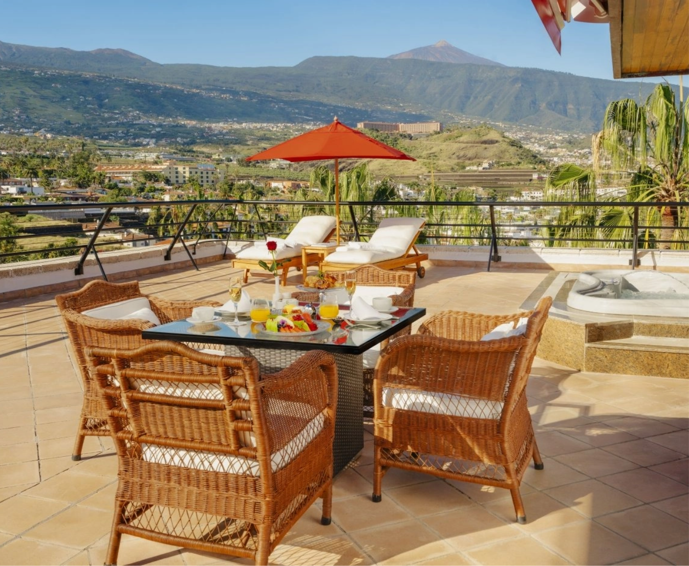 una mesa y sillas en una terraza con un paraguas rojo