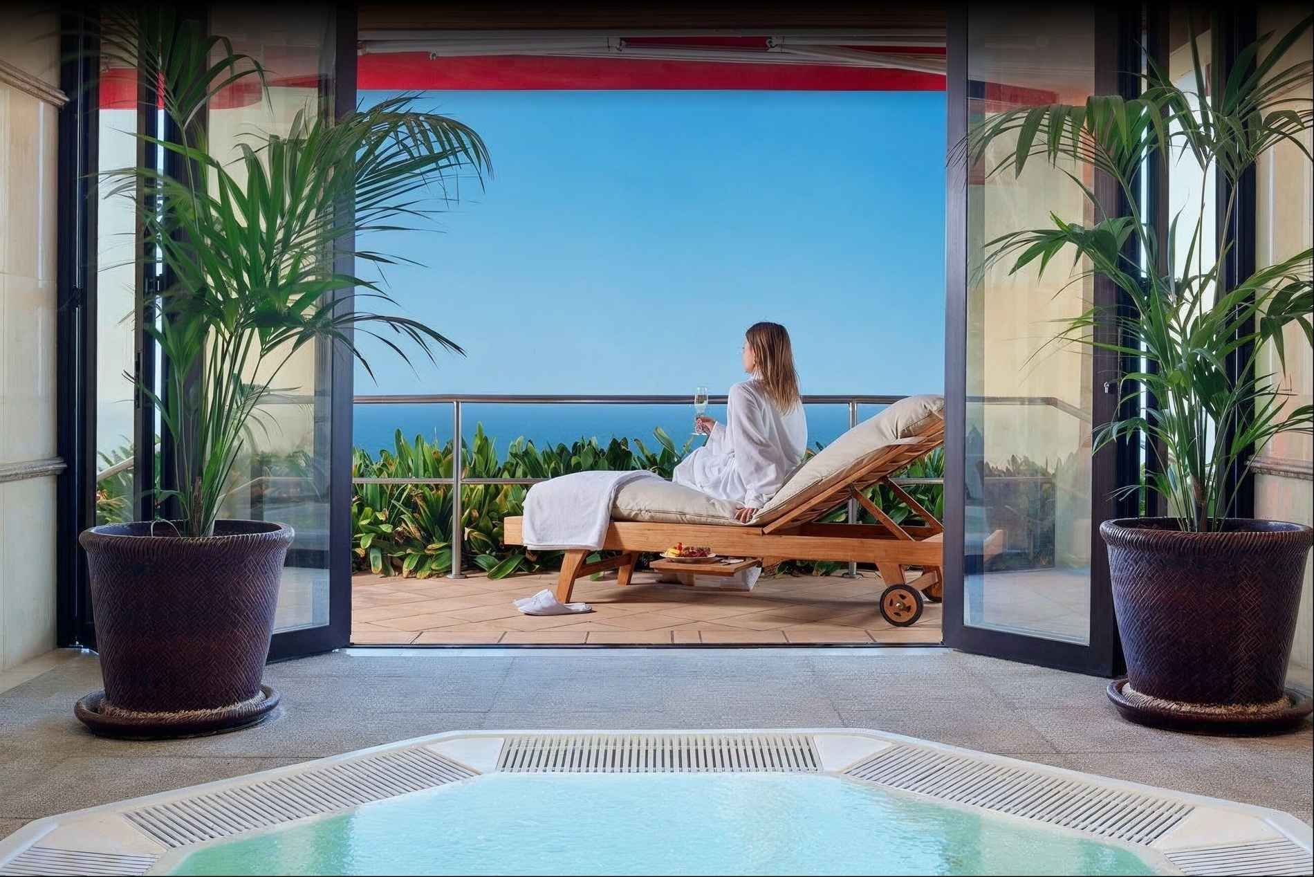 una mujer se sienta en una tumbona frente a una bañera de hidromasaje