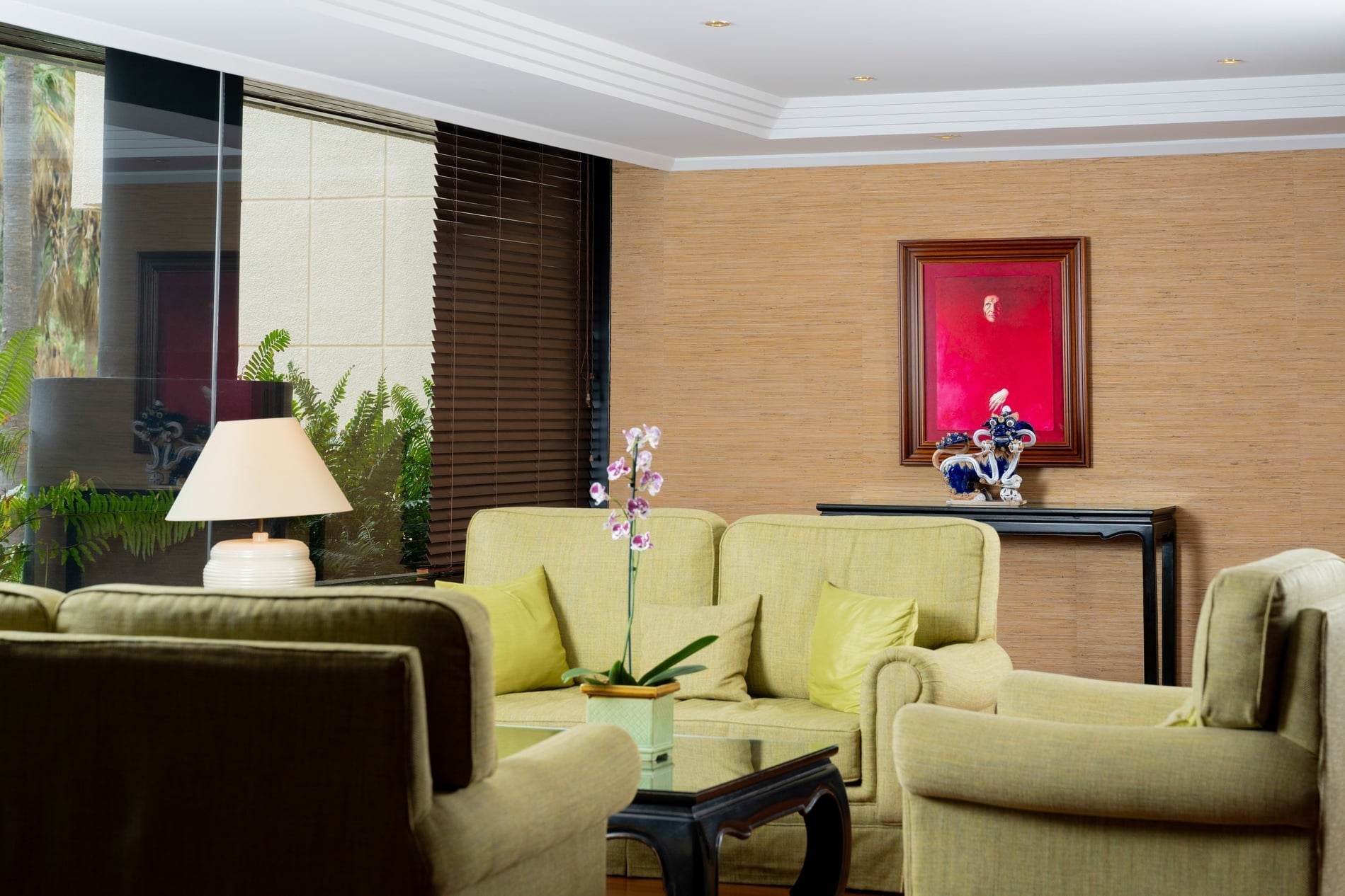 Un'elegante sala bar presenta un bancone in legno con sgabelli arancioni, sormontata dall'insegna "Bar Hall" e affiancata da un grande dipinto di una donna con un cesto di pesce su una parete rossa testurizzata.