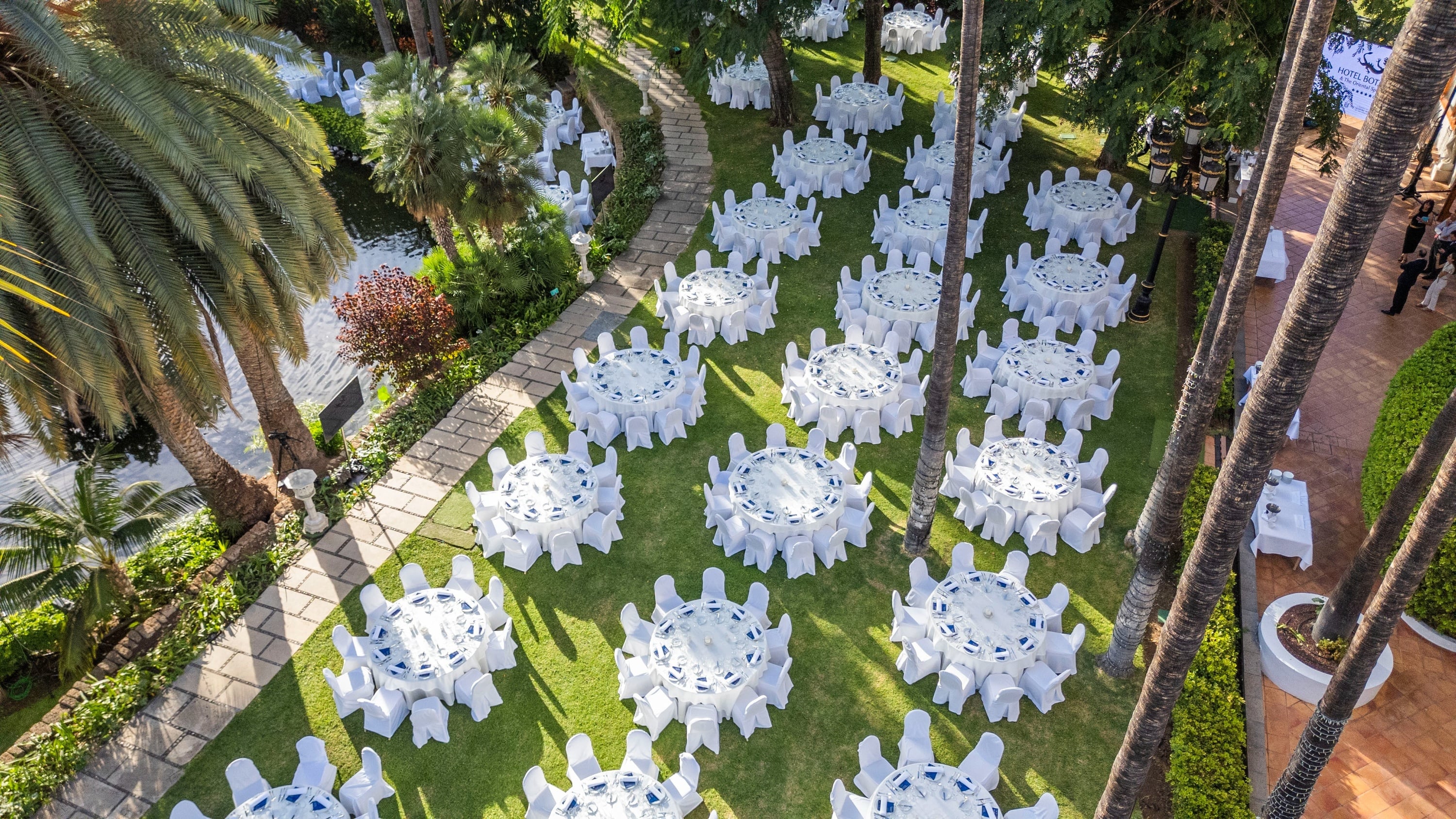 Cette image présente une longue table de banquet formelle, dressée avec des chaises de velours rouge et un centre de table floral, dans une salle élégante ornée de boiseries sombres et de rideaux dorés.