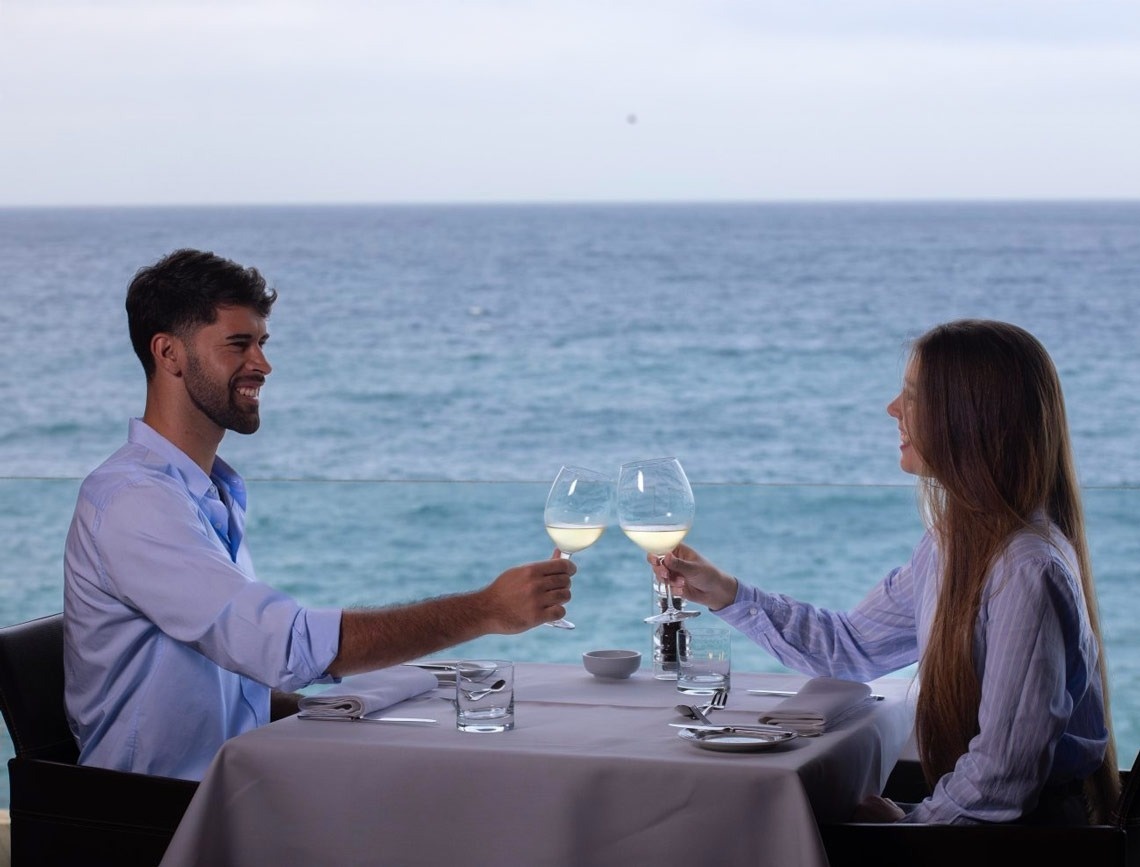 una donna è seduta a un tavolo mangiando pasta e bevendo vino