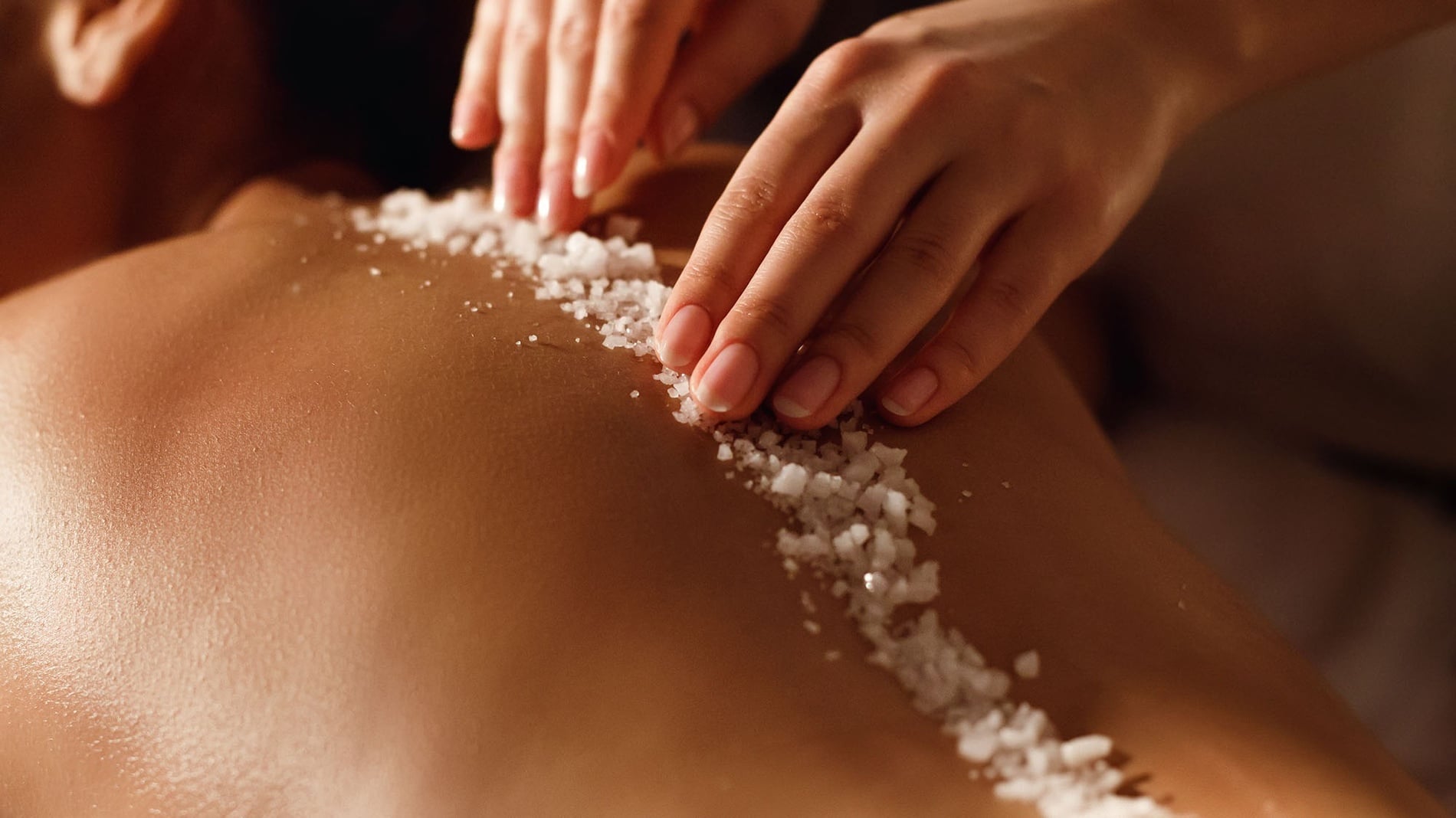 una mujer masajea la espalda de una persona con sal