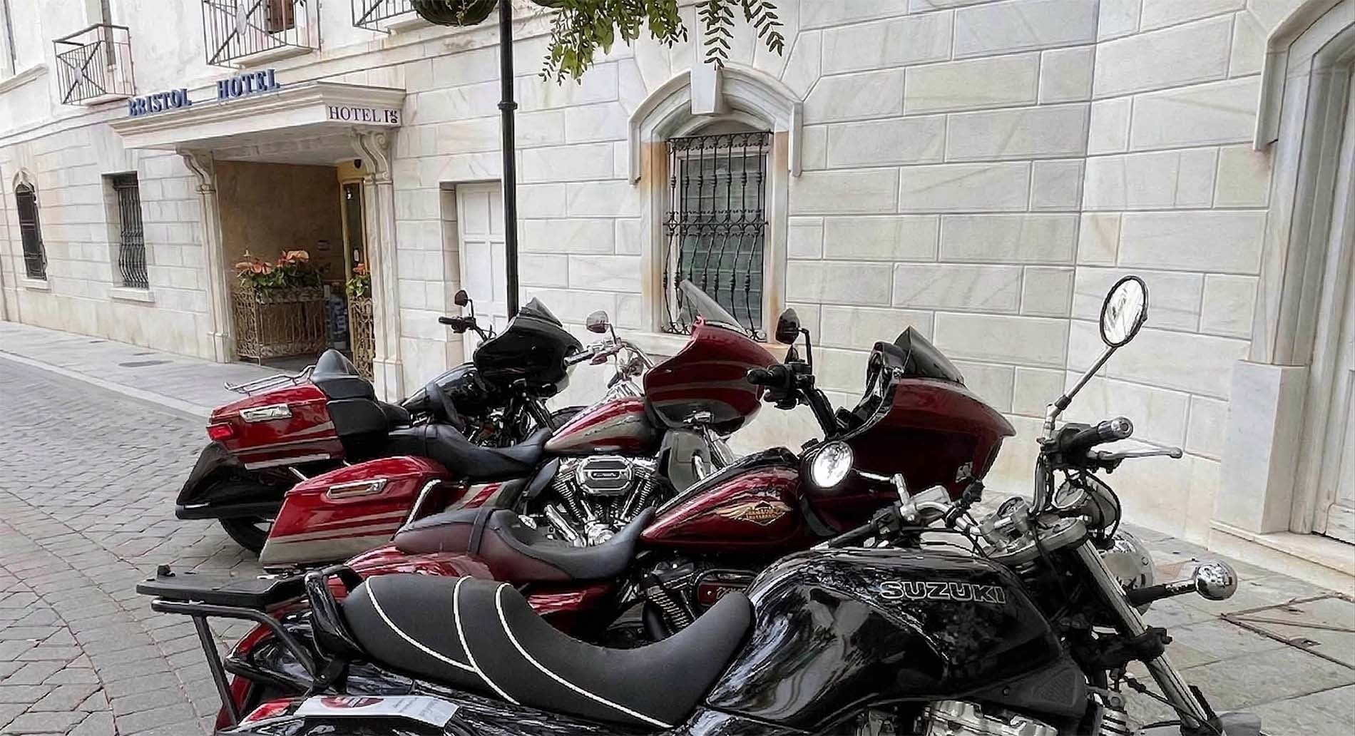 Bristol Hotel entrance, elegant white facade, with classic motorcycles parked outside.