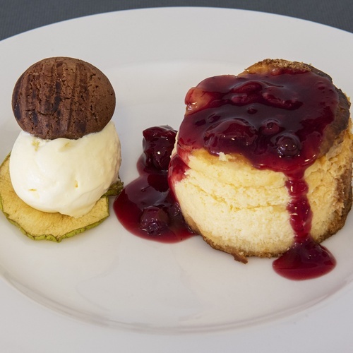 un plato blanco con un pastel de queso y helado