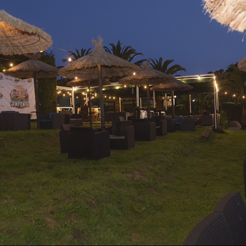 un patio al aire libre con sillas y sombrillas y una pancarta que dice ' fiesta en la playa '