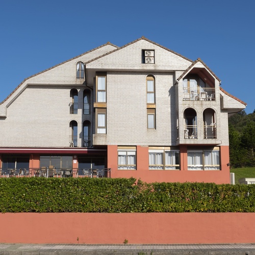 un edificio de ladrillo blanco y naranja con balcones y mesas