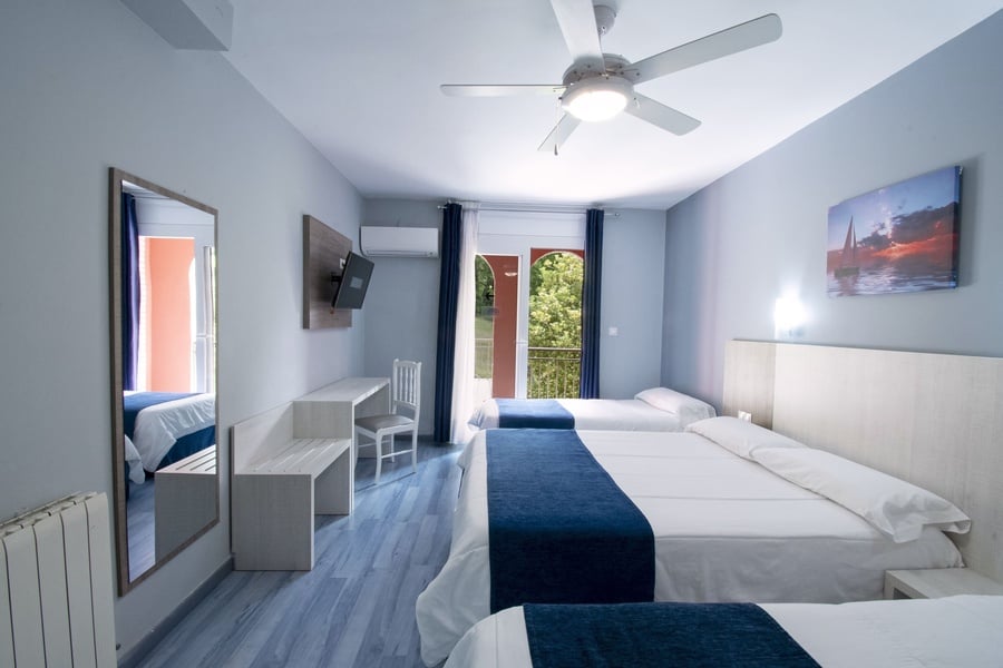 una habitación con tres camas y un ventilador de techo