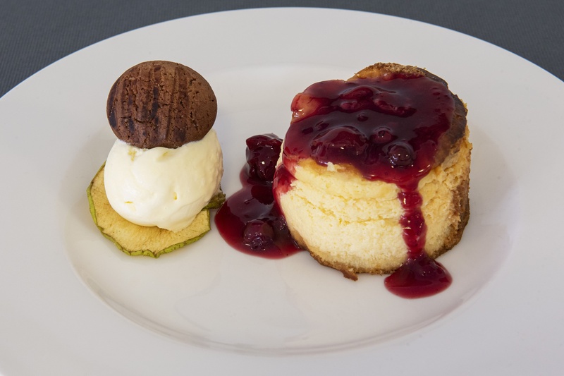 un plato blanco con un pastel de queso y helado