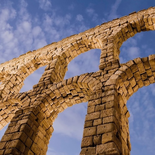 looking up at a stone archway with a blue sky in the background