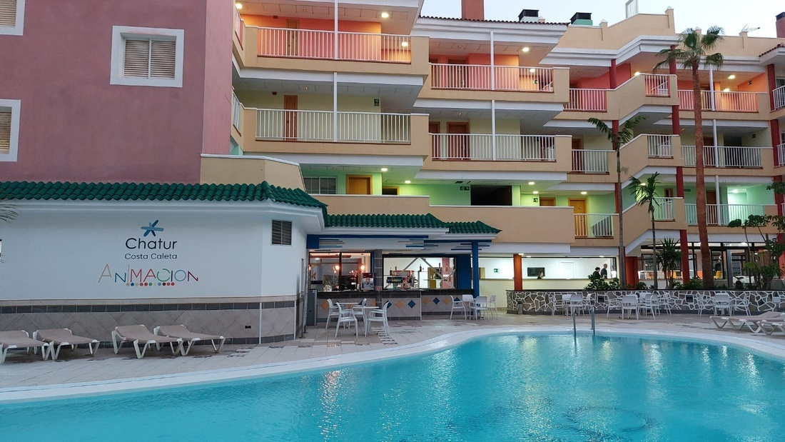 una piscina rodeada de edificios de apartamentos y un bar de animación