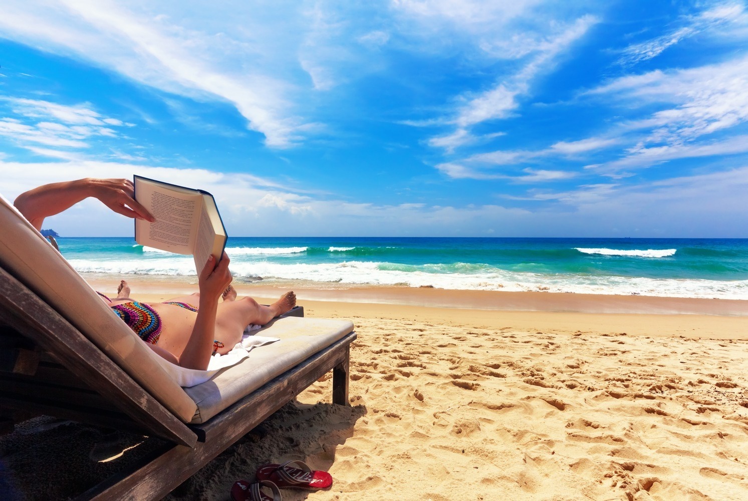 una mujer está leyendo un libro en la playa