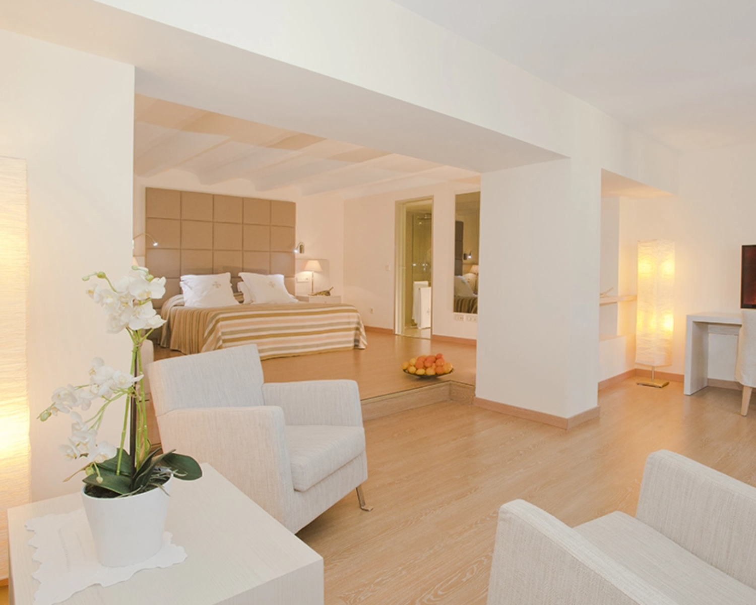 una habitación blanca con una cama y dos sillas