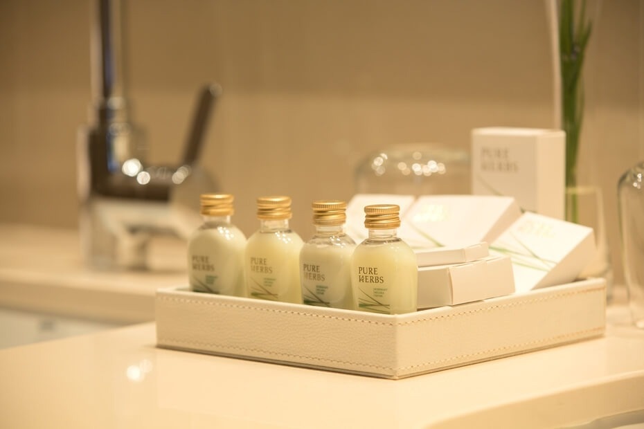 En un baño, una bandeja clara exhibe cuatro pequeñas botellas de artículos de tocador 