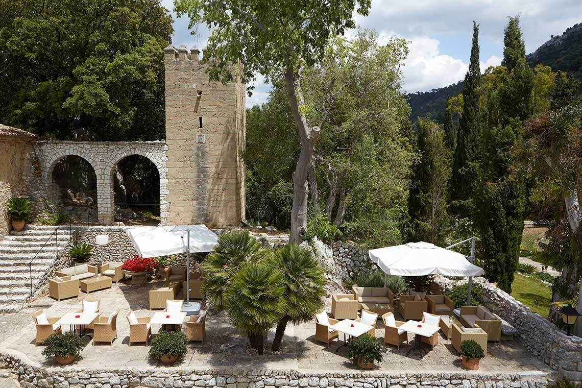 un patio con muebles y sombrillas frente a un edificio de piedra