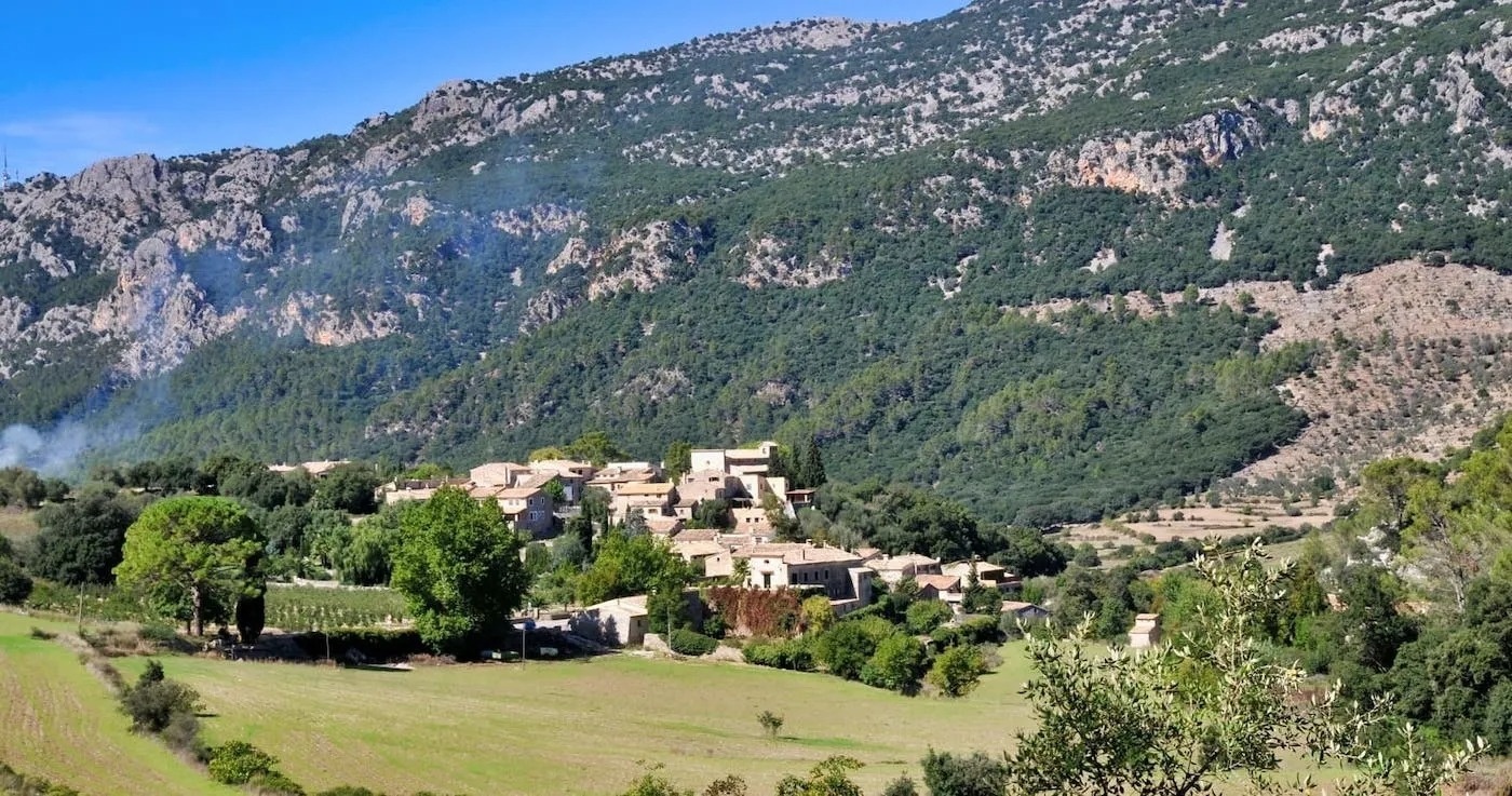 un pequeño pueblo está rodeado de montañas y árboles