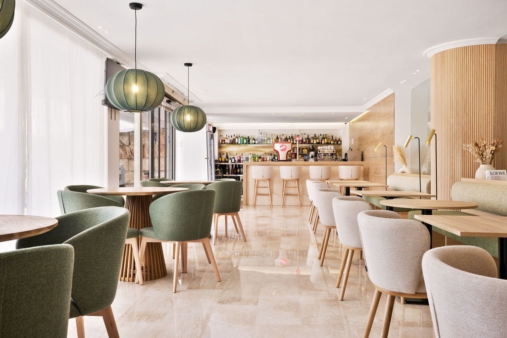 un restaurante lleno de mesas y sillas con un bar en el fondo .
