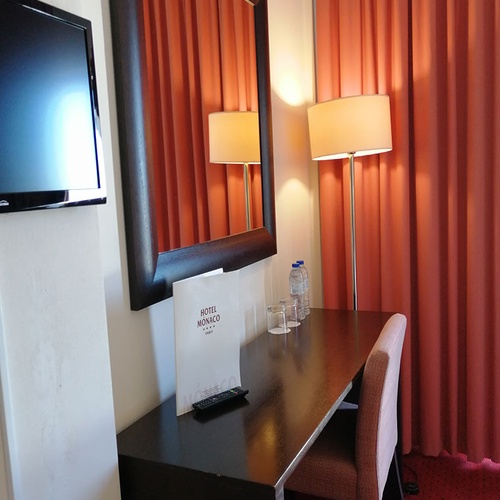 Escritorio en Hotel Monaco con espejo grande y lámpara de pie.