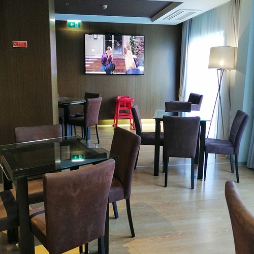 Amplia zona de estar y mesas en Hotel Monaco con TV y silla alta para niños.
