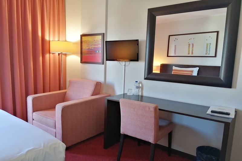 Quarto no Hotel Monaco com cama, poltronas e espelho grande.