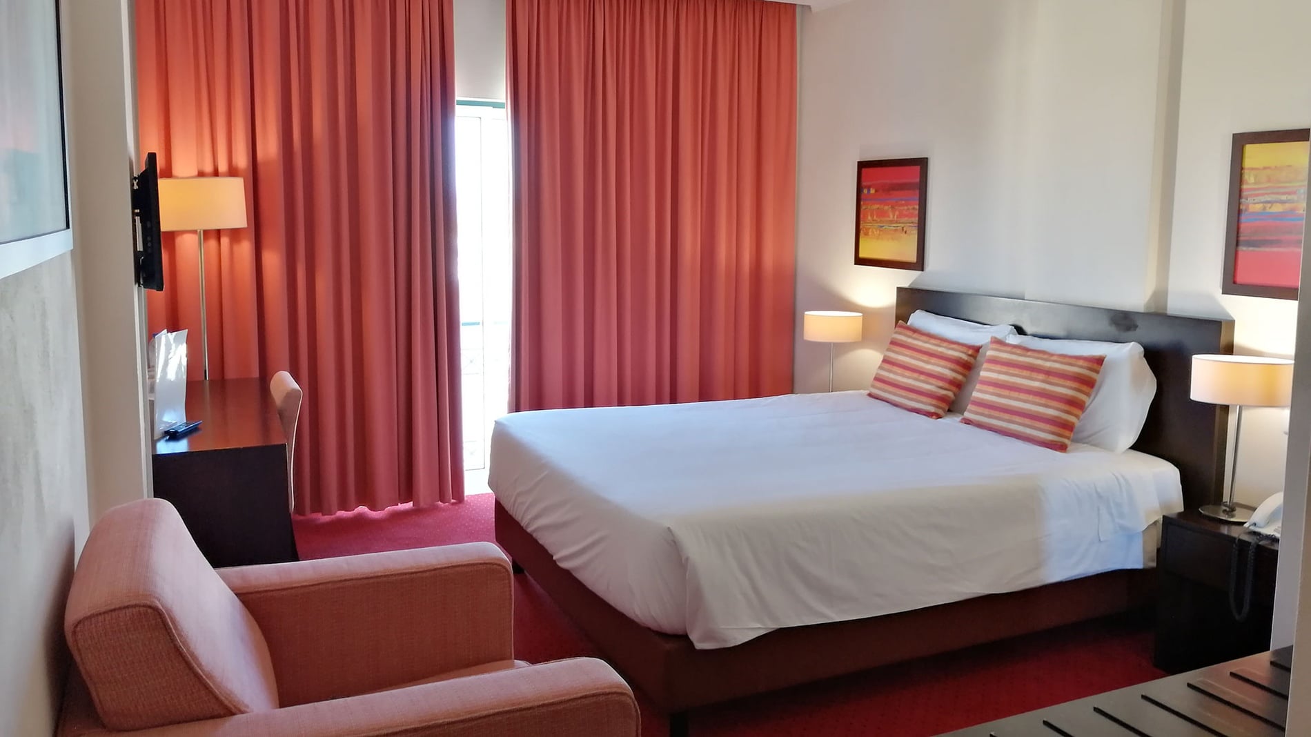 Quarto elegante no Hotel Monaco com cama confortável, cortinas, arte e luminárias.