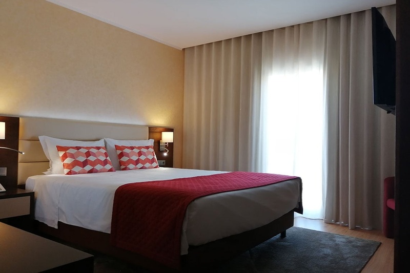 Quarto de hotel confortável no Hotel Monaco com cama branca, colcha vermelha e almofadas decorativas.