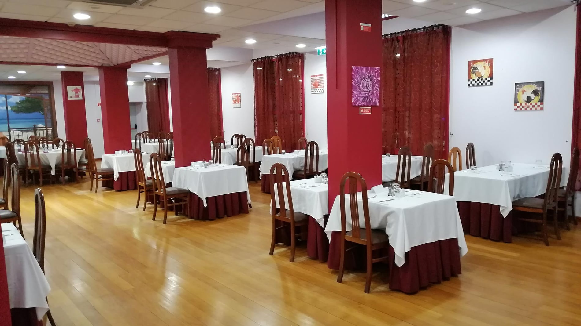 Sala de jantar do Hotel Monaco com mesas postas e cadeiras de madeira.